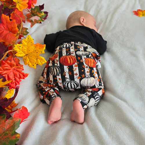 Sleeping Baby Wearing Black & White Striped Pumpkin and Autumn Leaves Print.